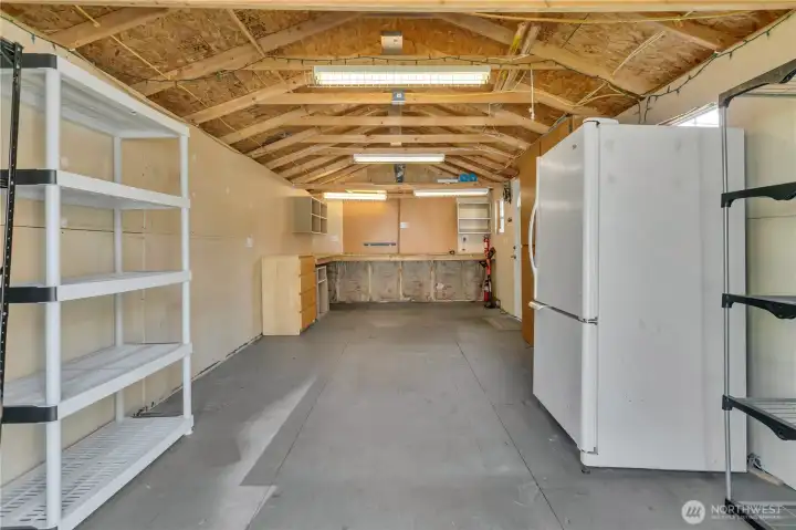 Outdoor shed has lighting and is clean and spacious, could be a perfect workshop or storage spot.