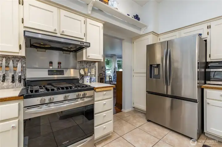 A kitchen view emphasizing the cooktop/oven and refrigerator. The gas cooktop features and overhead hood for ventilation A kitchen view emphasizing the cooktop/oven and refrigerator. The gas cooktop features and overhead hood for ventilation