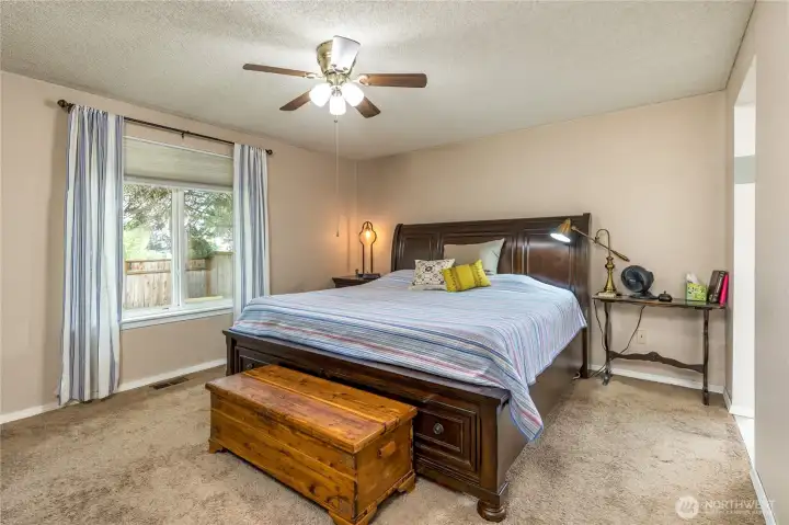 The primary bedroom, with excellent natural lighting, a fan/light combination, and carpeting The primary bedroom, with excellent natural lighting, a fan/light combination, and carpeting