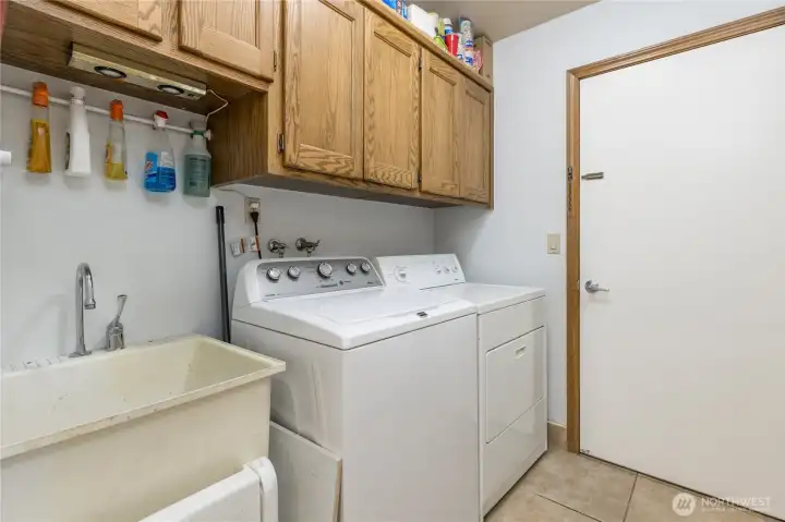 The laundry/utility room, with vinyl flooring, cabinets and a sink The laundry/utility room, with vinyl flooring, cabinets and a sink