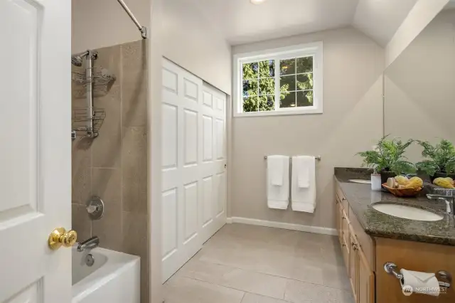 The generously sized hall bathroom features  a battub, dual vanities, and ample storage  space, providing both comfort and  convenience.