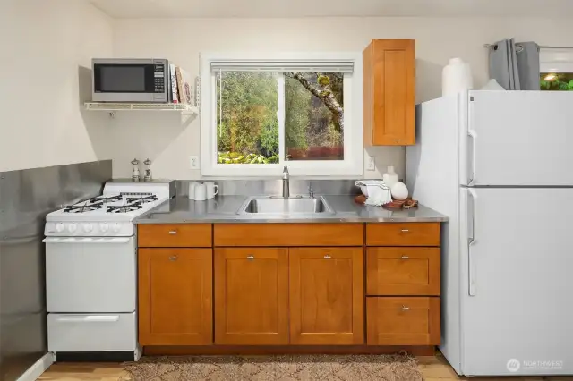 The cottage features a fantastic kitchenette  complete with a range, refrigerator, and  even offers scenic views from the kitchen  sink!