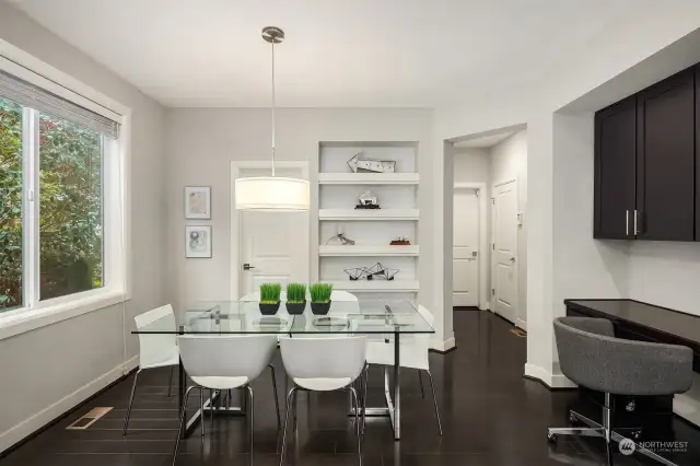 This informal eating space is perfectly situated adjacent to the kitchen and can accommodate a large dinner table. The closed door pictured behind the table is the walk in pantry. Also pictured is a custom built-in workspace that was installed by the sellers.