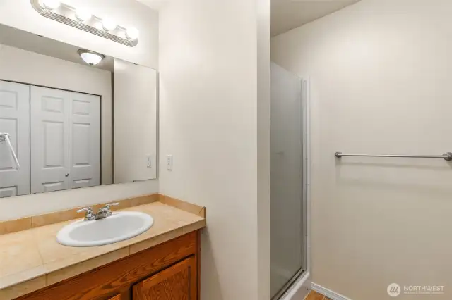 The Guest Bathroom is located across the halllway from Bedroom #2 and features a walk-in shower & commode area, vanity with sizable mirror and a Laundry Area to the right.