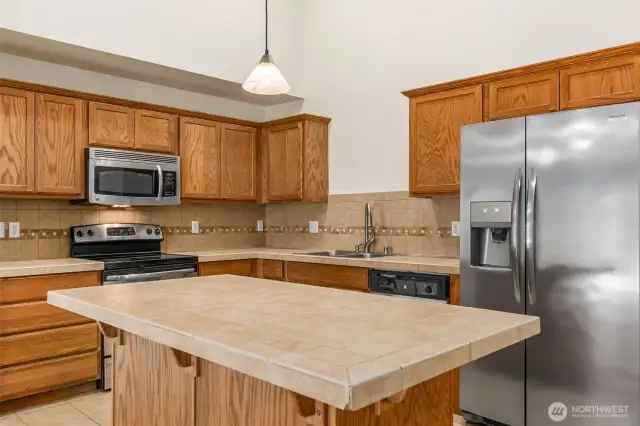 The stylish Kitchen features warm oak cabinetry, stainless steel appliances & ceramic tile counters, backsplash & flooring.