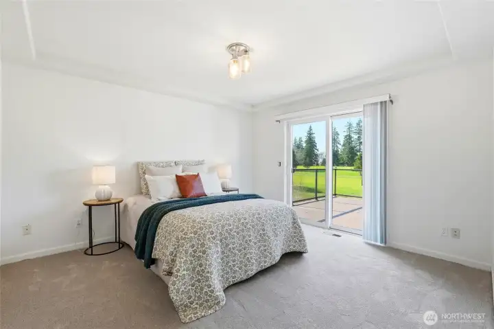 Serene main-level primary suite with a private sliding door to the deck, where westerly views set the stage for glowing sunsets and summer fireworks.