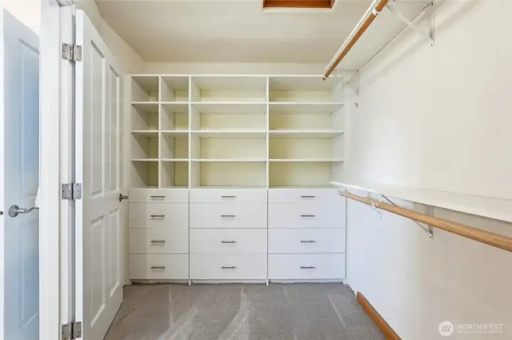 Spacious walk-in closet with custom built-ins, abundant shelving, and multiple drawers for organized storage.