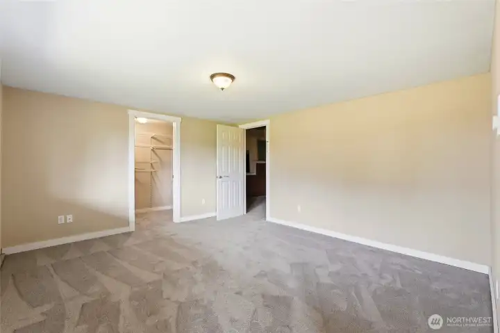 ADU primary bedroom with an oversized walk-in closet featuring a built-in organization system and door to more storage space.