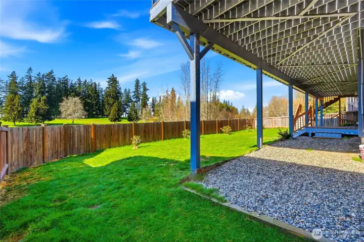 A quiet retreat: covered ADU deck overlooking lush lawn and tranquil scenery beyond the fence.