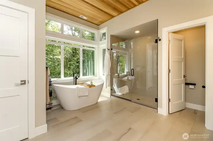 Notice the tounge and groove ceiling and the huge windows in this exquisite five piece bathroom retreat which looks out to the trees backyard.  Linen closet too!