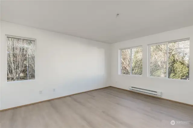 Primary bedroom has large windows and lovely tree views