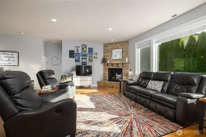 This great room is anchored by the hardwood flooring and stone-clad natural gas fireplace.