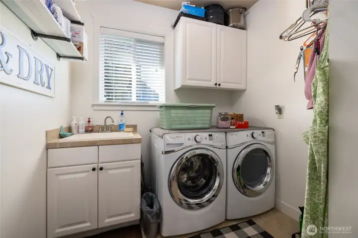 Main floor laundry room has a utility sink, tile flooring, lots of natural light.