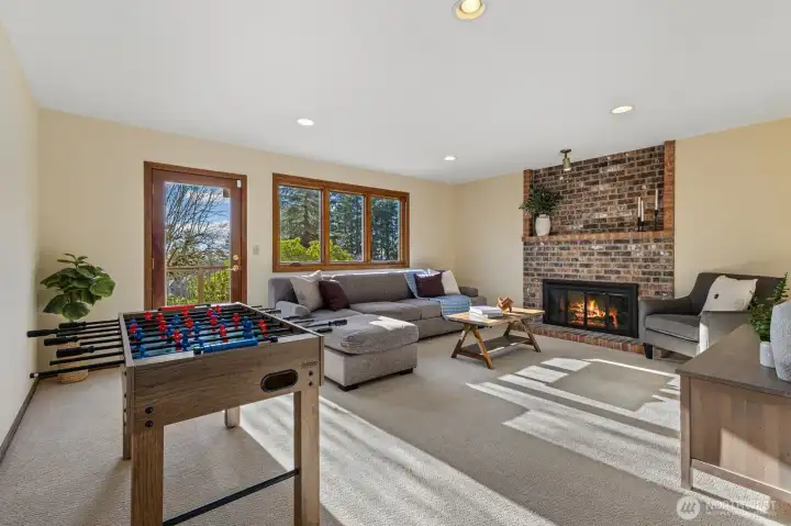 Daylight basement level bonus room with a wood-burning fireplace and access to the second large deck with additional backyard access.