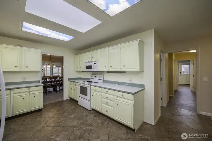 A view of the kitchen with access to the dining room to the left, pantry, laundry, garage, and side door exit.