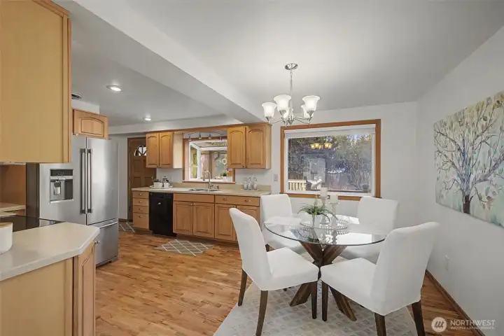 Kitchen and dining area with hardwood floors, generous cabinet storage, and a bright eating space overlooking the backyard.