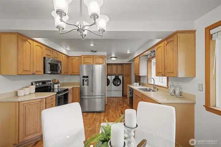 Spacious kitchen with abundant cabinetry, stainless appliances, and hardwood floors, with laundry conveniently nearby.