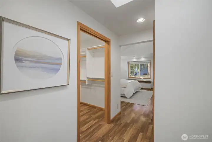 Entry to the primary bedroom with walk-in closet and hardwood flooring.