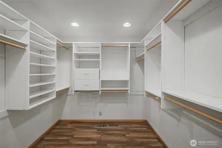 Large walk-in closet featuring custom shelving, drawers, and ample hanging space.