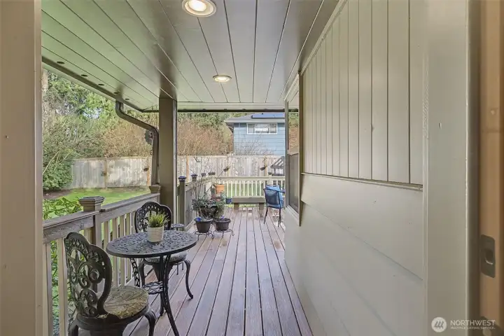 Private covered porch off the primary suite, ideal for morning coffee or quiet outdoor time, overlooking the fenced yard and mature landscaping.