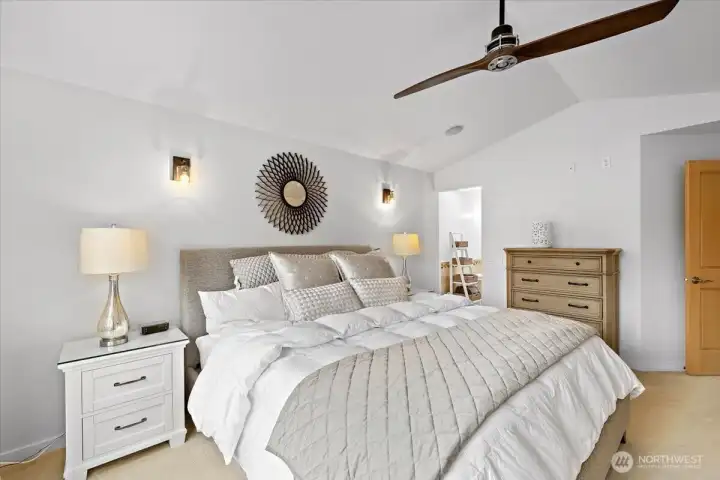 Spacious primary bedroom featuring a vaulted ceiling, ceiling fan, and generous floor space.