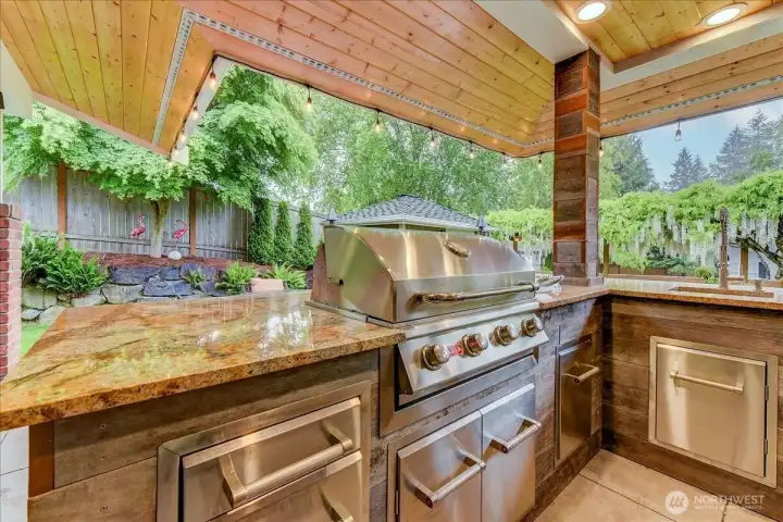 Stunning outdoor kitchen featuring slab granite countertops, a built-in BBQ, a separate gas burner, and a convenient ice maker.
