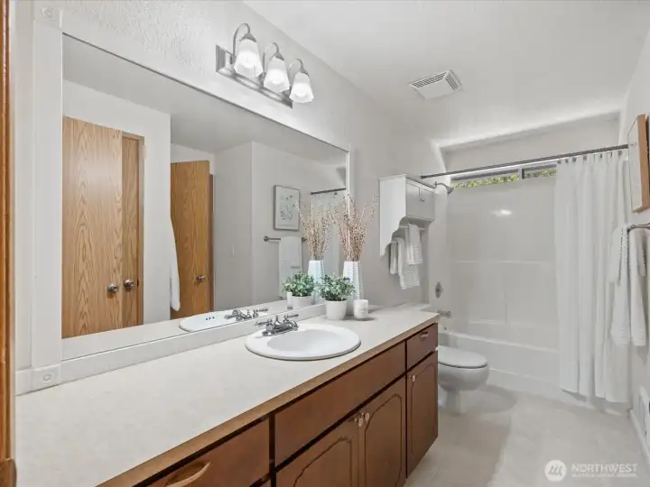 The well designed bathroom opens to the hallway and primary bedroom and includes vanity storage and a linen closet.