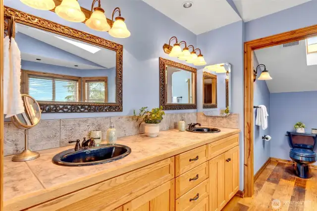 Primary bathroom vanity with double sinks. Gorgeous wood flooring. The spa-like 5-piece bathroom with stunning views.
