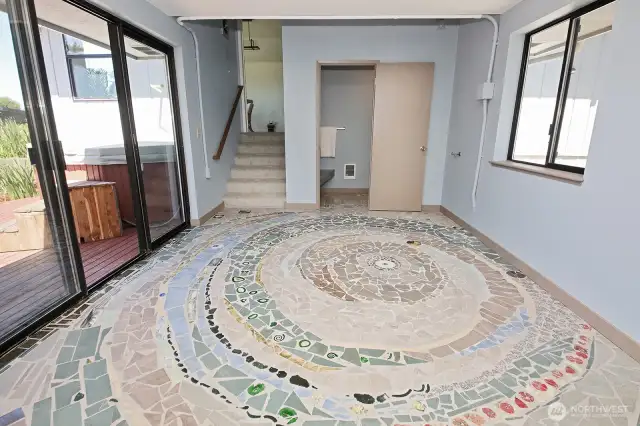 Custom tiled Spiral design in the room that joins the main house to the Primary Suite Guest Space. Sliding doors take you to the deck. Stairs lead you to the Primary Suite.