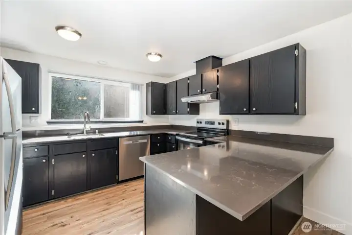 Kitchen boasts plenty of cabinet and counter space with expansive window above the sink that pours in natural light.