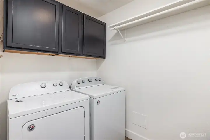 Downstairs laundry room with storage and hanging shelf.