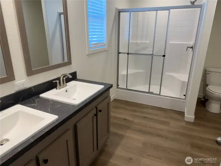 Primary bath w/double vanities and walk in shower. NOTE: Picture is of a different home w/same floor plan so colors may be different.