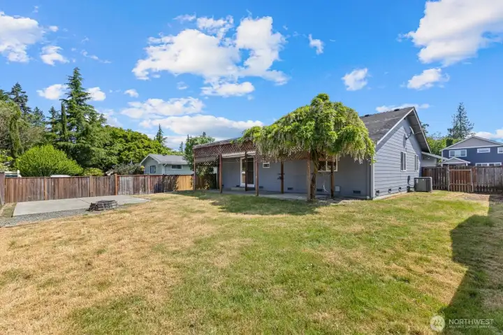 Back of the home & fenced in yard. Wisteria growing on the trellis.
