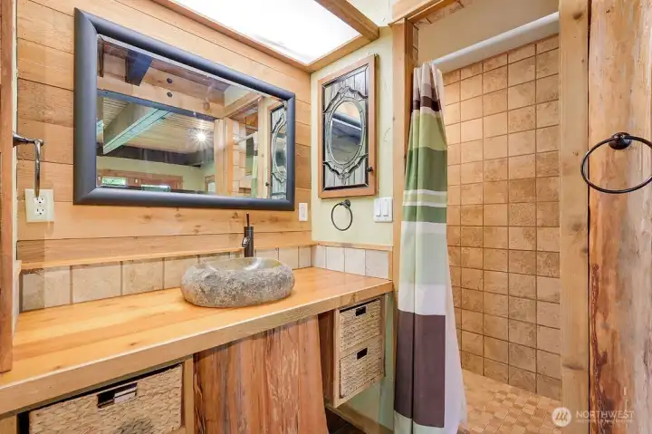 Primary bedroom with 3/4 bath has a stone vessel sink, tiled floors, and character throughout.