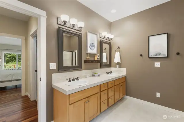 A posh, spa like attached primary bath has a relaxing soaking tub, shower, and double vanity sink.