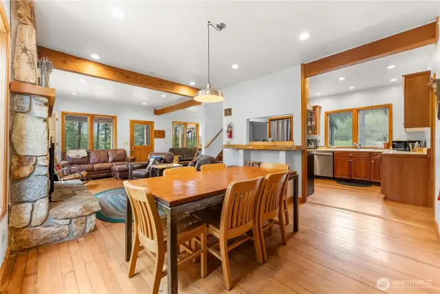 Open-concept kitchen, dining, and living areas with timber beams and wood floors—designed for gathering and easy mountain living