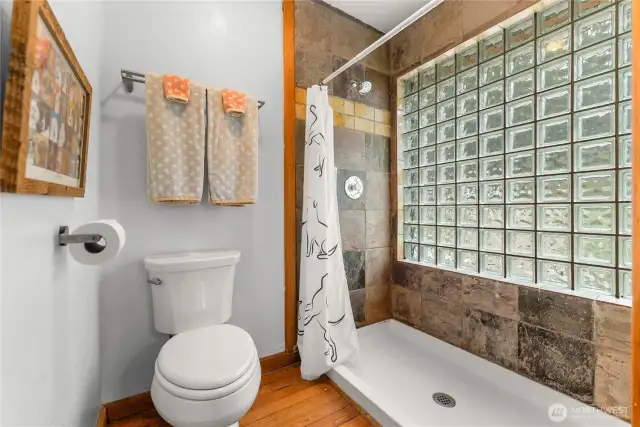 Bright, updated bath with glass block window, slate tile accents, and spacious walk-in shower—simple, sturdy, and stylish