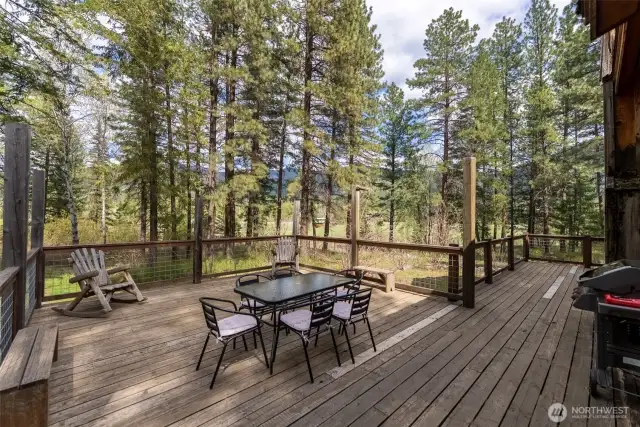 Spacious wraparound deck with dining and lounge areas—perfect for entertaining or relaxing in the pines