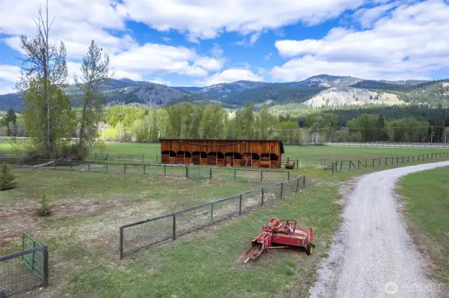 Pastoral setting; graveled ranch road, classic stall barn, and wide-open pasture—ready for livestock, legacy, or both