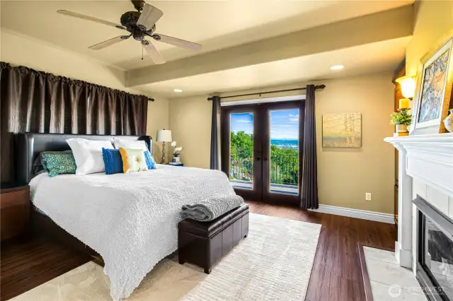 Luxurious primary suite featuring a cozy gas fireplace and French doors that open to a private deck—perfect for enjoying stunning views morning or night.