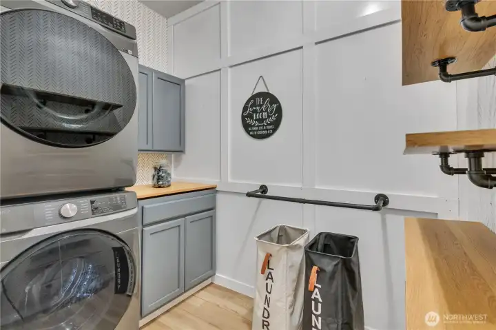 Darling laundry room is packed with utility with built in cabinetry, folding space, open shelving and built in areas for air drying delicates.