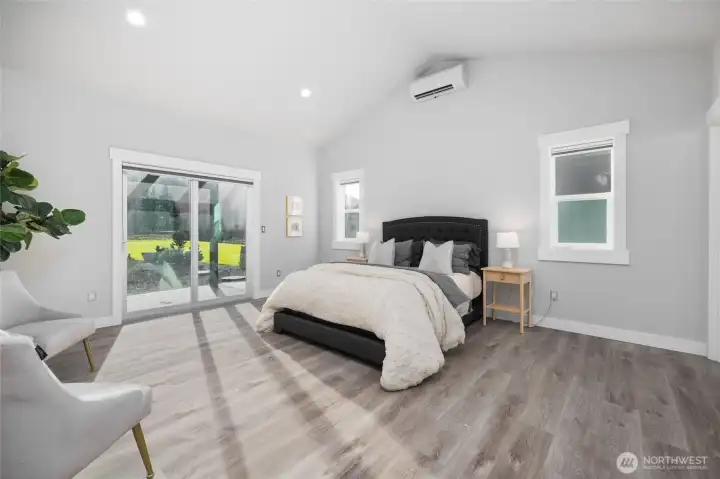 Main floor primary suite, with sliding glass door to the patio beyond.  Vaulted ceiling, mini ductless split AC, plus radiant in-floor heat.