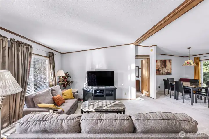 Another view of the living room with the primary bedroom suite at center and the dining room on the right