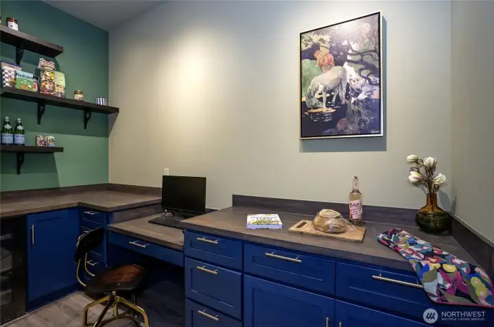 Elevate everyday living with a walk-in pantry featuring custom navy cabinetry, rich wood countertops, a built-in beverage fridge, and a dedicated workspace for recipes, weekly menus, and grocery lists — blending luxury with exceptional functionality.