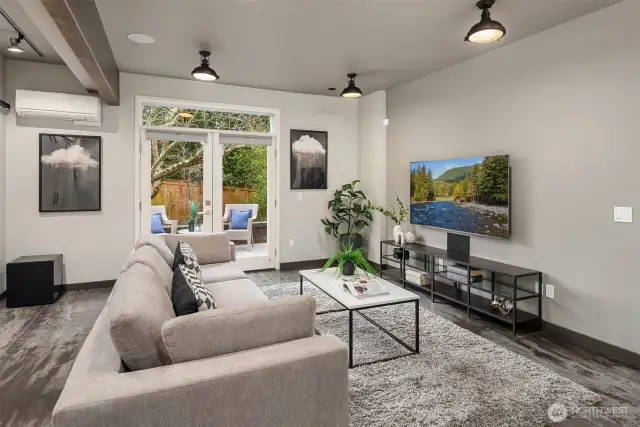 Contemporary family room showcases French doors to private patio, industrial lighting, and elegant architectural details.