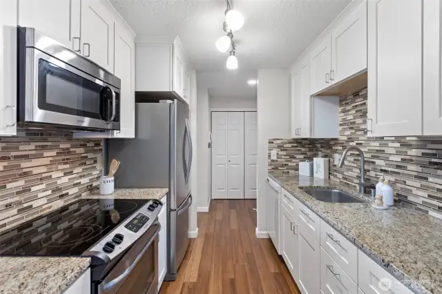 Frigidaire range & microwave, Whirlpool double door fridge with bottom freezer drawer, Blomberg dishwasher and custom lighting completes this kitchen space.