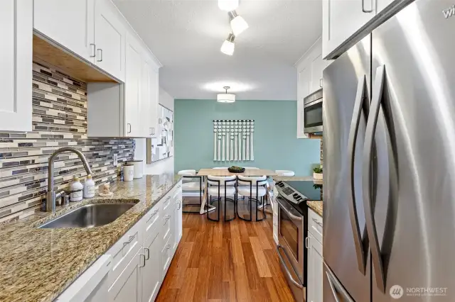 Updated kitchen with gorgeous granite counters and glass backsplash,  soft closing J & K cabinetry and Hansgrohe faucet.
