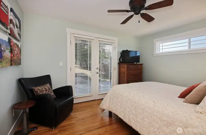 1st bedroom downstairs with french doors to deck and back yard beyond.