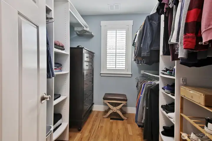 Walk-in primary closet has window for ventilation and wonderful built-ins.