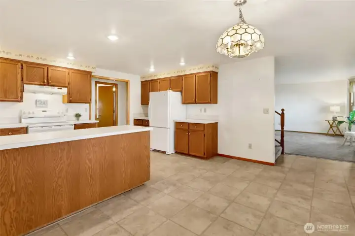 The kitchen features a U-shaped workspace plus a bank of cabinets on the opposite wall.